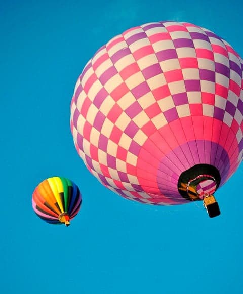 Colorful hot air balloons floating high in a blue sky